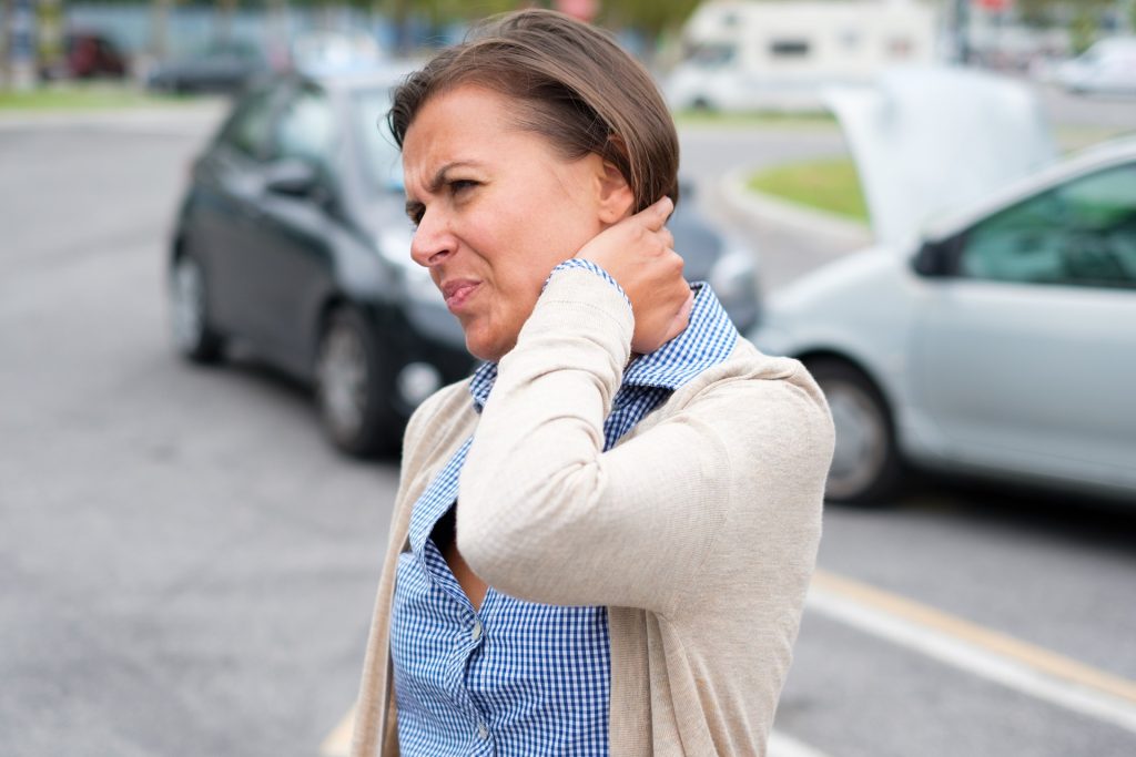 Woman holding the side of her neck as if experiencing neck pain